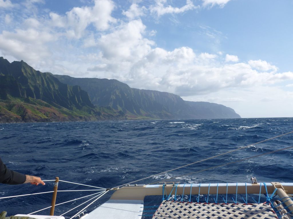 Na Pali Coast's dramatic green cliffs and turquoise ocean viewed from a boat tour off the coast of Kauai