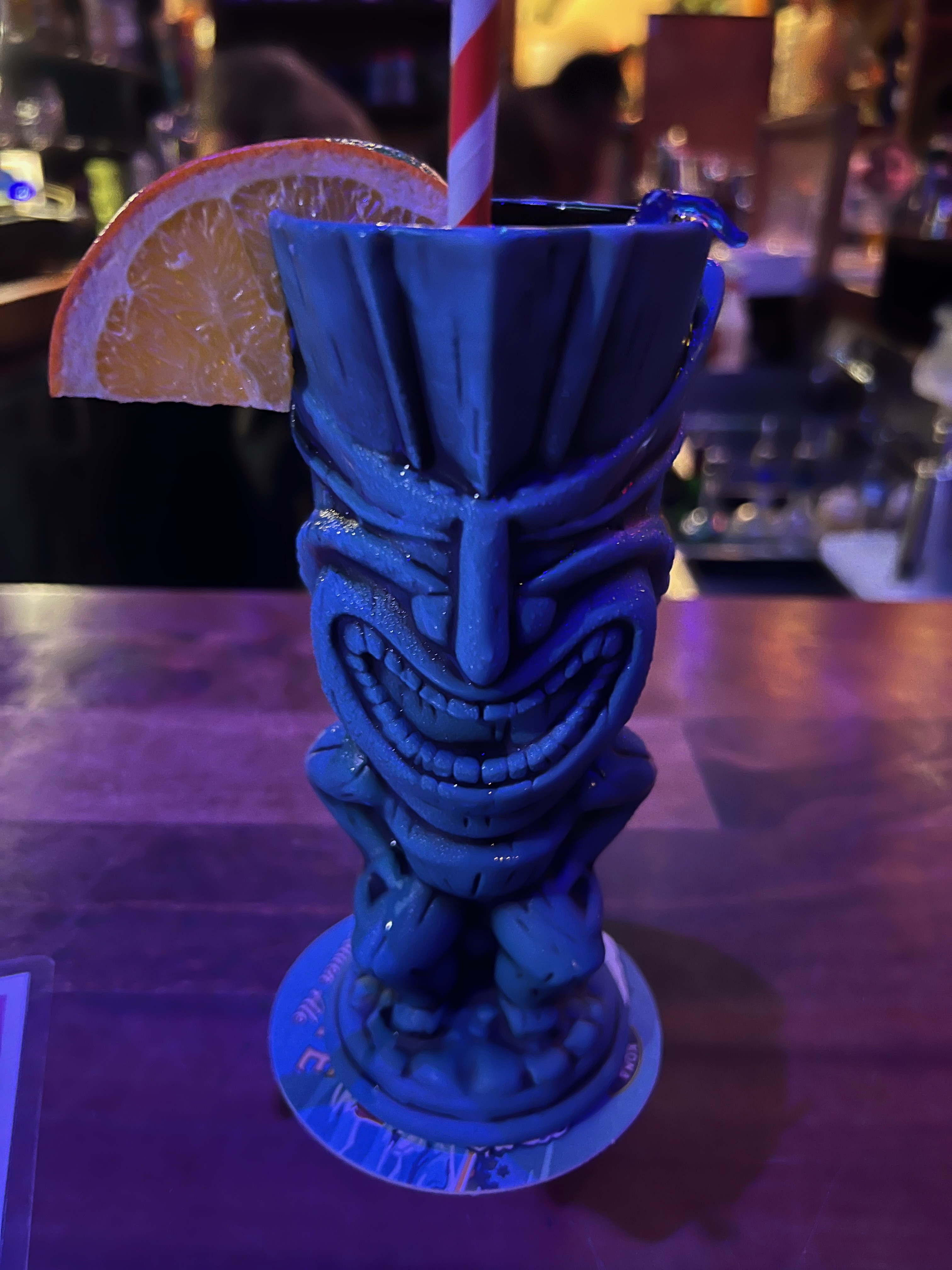 Green tiki mug with an orange garnish sitting on a bar at Tiki Iniki in Princeville, Kauai
